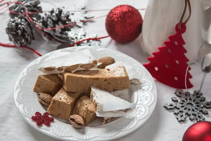 Typical dessert for Christmas, spanish turron served in white plate and background