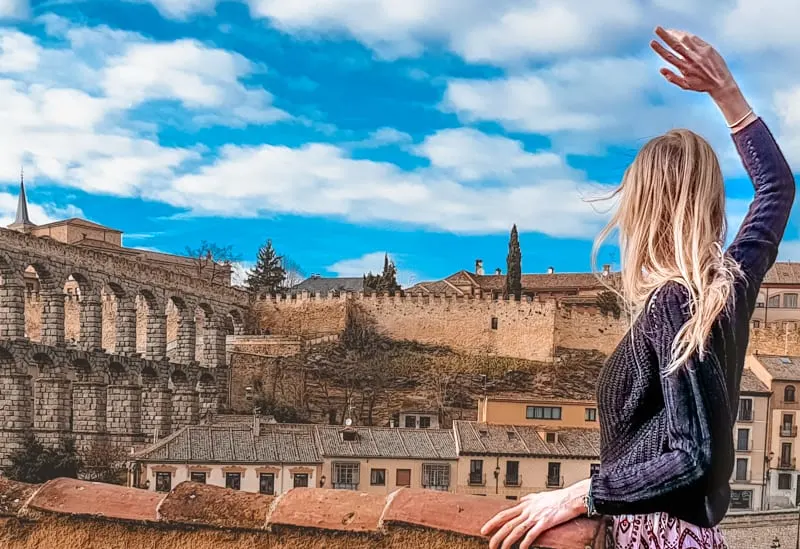 a woman facing back at the camera looking at a segovia aqueduct, day trip from madrid to segovia, madrid day trip to segovia, segovia day trip, how to et form madrid to segovia, segovia itinerary