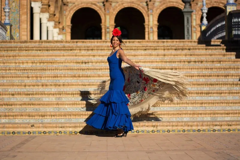 spanish girl on a blue flamenco dress dancing flamenco in seville, spain