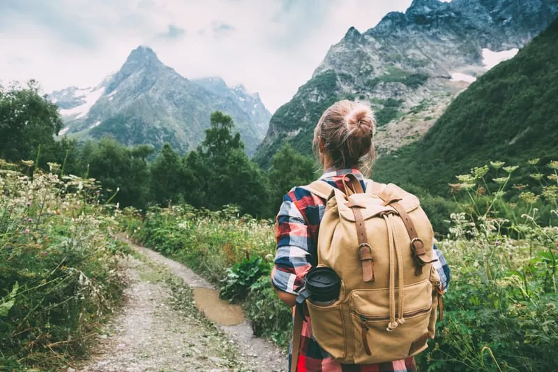 a woman walking to the mountain with a backpack, hiking coffee table books