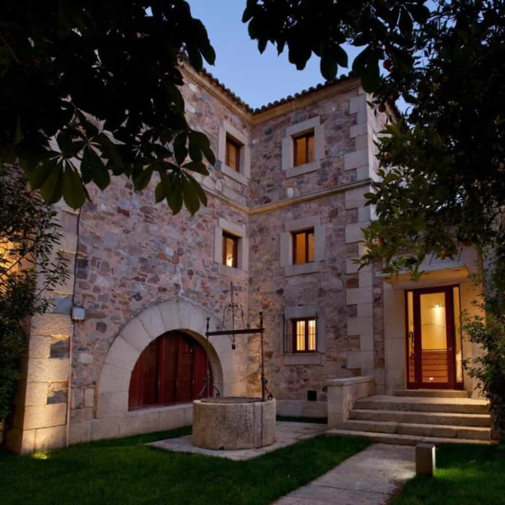 a corener of a stone house at night with steps leading up to the front door with trees