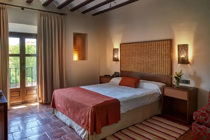 It's time to book your rooms in these spanish paradores, interior of hotel room with double bed and other furniture arranged with tasteful decor and pleasant lighting