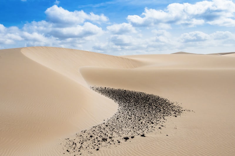 Don't miss these things to see in sal cape verde, sweeping sand dunes rolling smoothly into the distance under an azure blue sky with white fluffy clouds