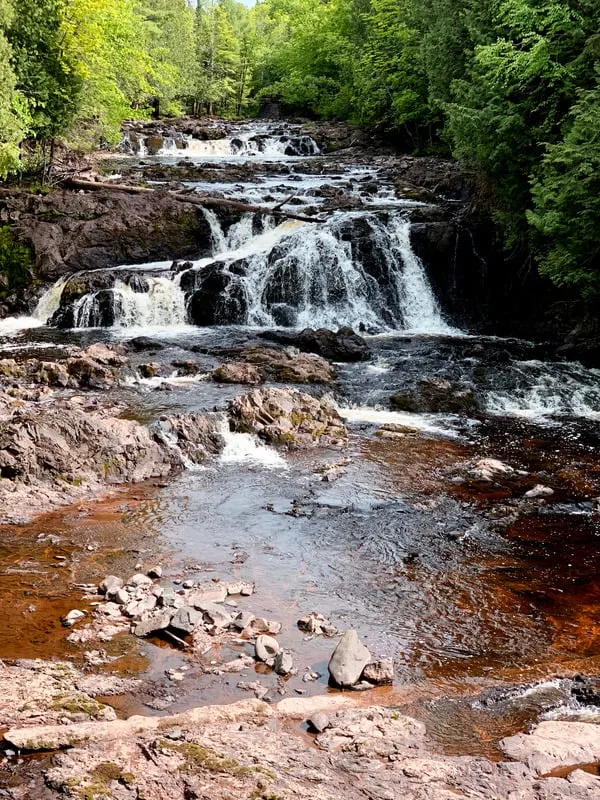 levels of the Waterfalls with trees on the upper part  and reddish sand on the forefront in  in Copper Falls State Park Wisconsin