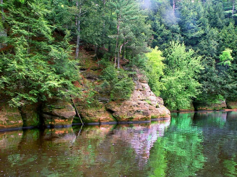 Rocky cliffs and vegetation in the Wisconsin Dells reflected in a lake