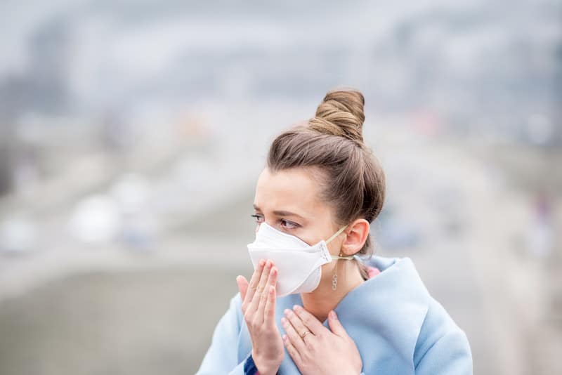 Young woman in protective mask feeling bad in the city with air pollution from traffic and manufacturing. Smog concept, coronavirus in spain, coronavirus in tenerife, woman with mask