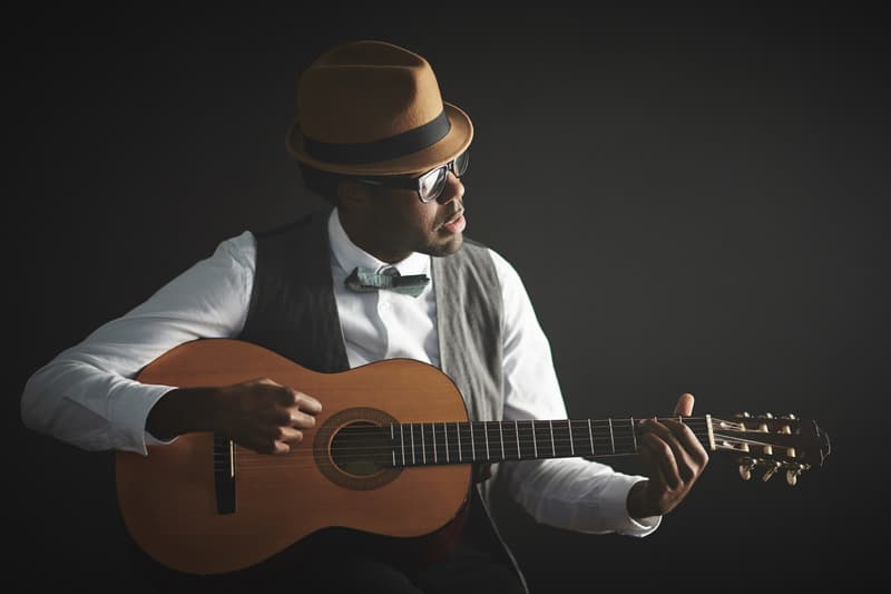 things to do in Minocqua at night, elegant young man in smart clothes and hat playing guitar