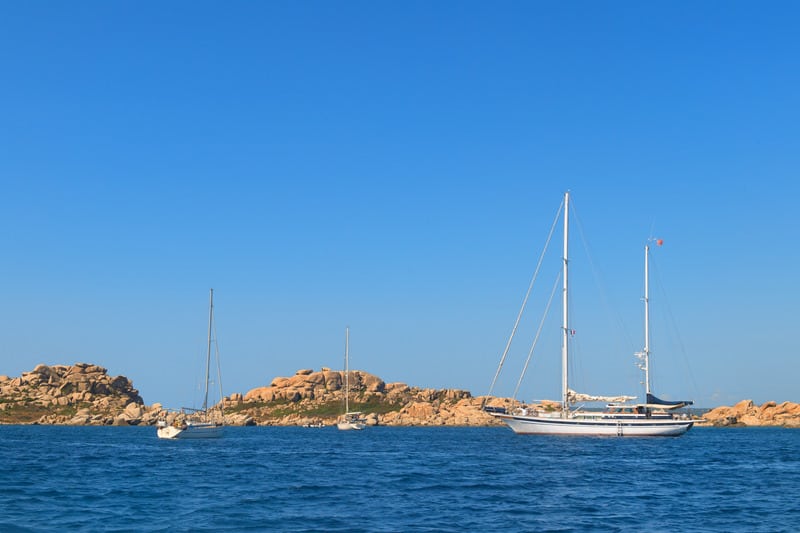 yachnts near rocks which looks like islands on a blue sea on a bright day