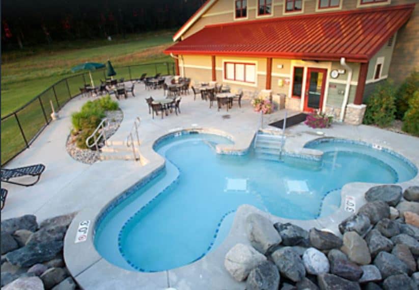 Top outside view of a cabin at Christmas Mountain Village Resort with a small pool and some outside chairs and tables