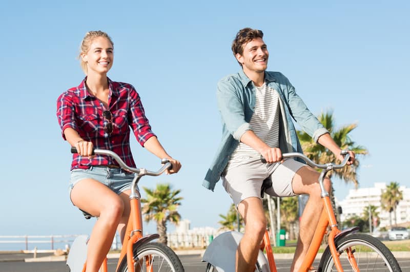 Staycation Ideas, Active young couple riding bikes during summer vacation.