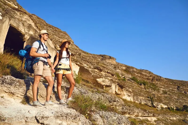 Staycation Ideas for Couples, Happy hiking couple with backpack On a hike in mountains.