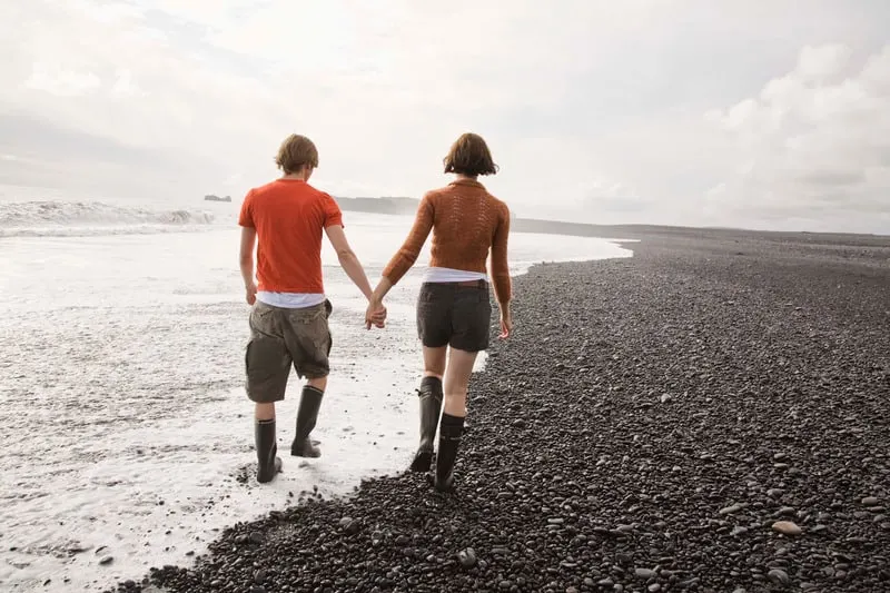 Staycation Ideas for Couples, Couple taking walk, holding hands on beach