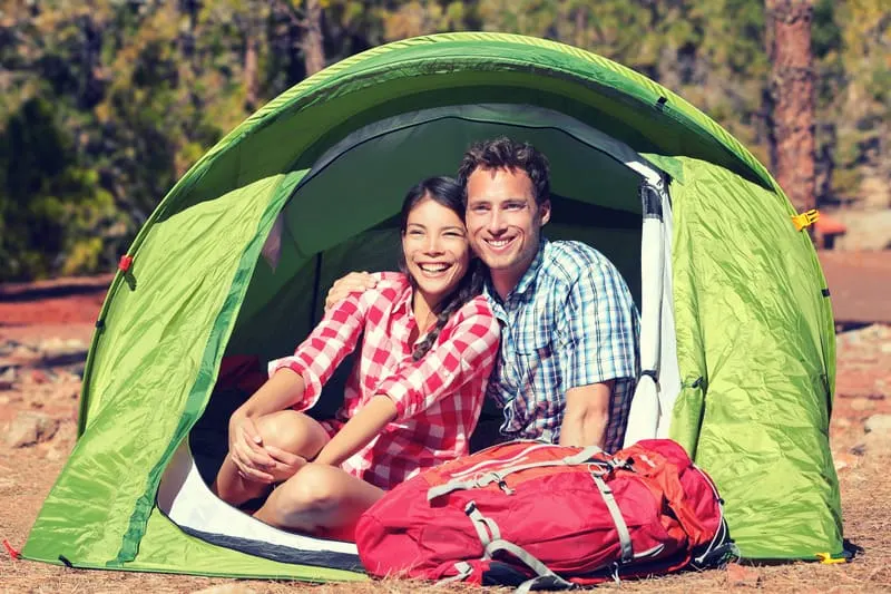 staycation ideas for couples, Happy hiking couple resting in green tent.