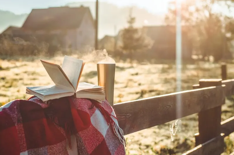 Breakfast with a book in the open air. Steam over a thermo cup. Open book on nature