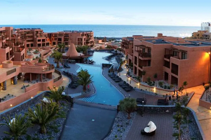 Try out the best family resort in Tenerife, Top view of Sandos San Blas Eco Resort with a view of a long series of swimming pools winding between tall brown apartment blocks looking out towards the sea