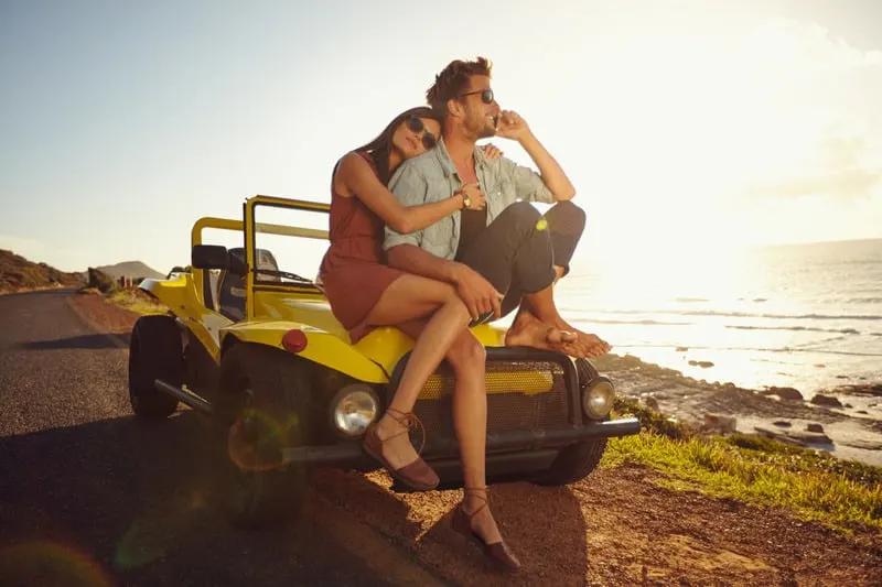 Staycation ideas for couples, Couple on a off road trip sitting on a trophy truck jeep