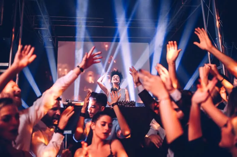 people partying and raising their hands up with a dj playing music