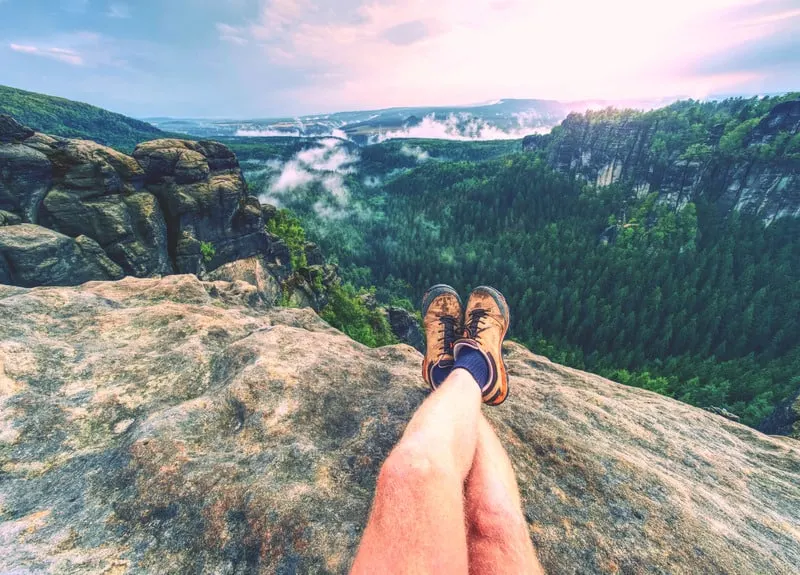 Hiking boots on hiker outdoors walking crossing rocky trail