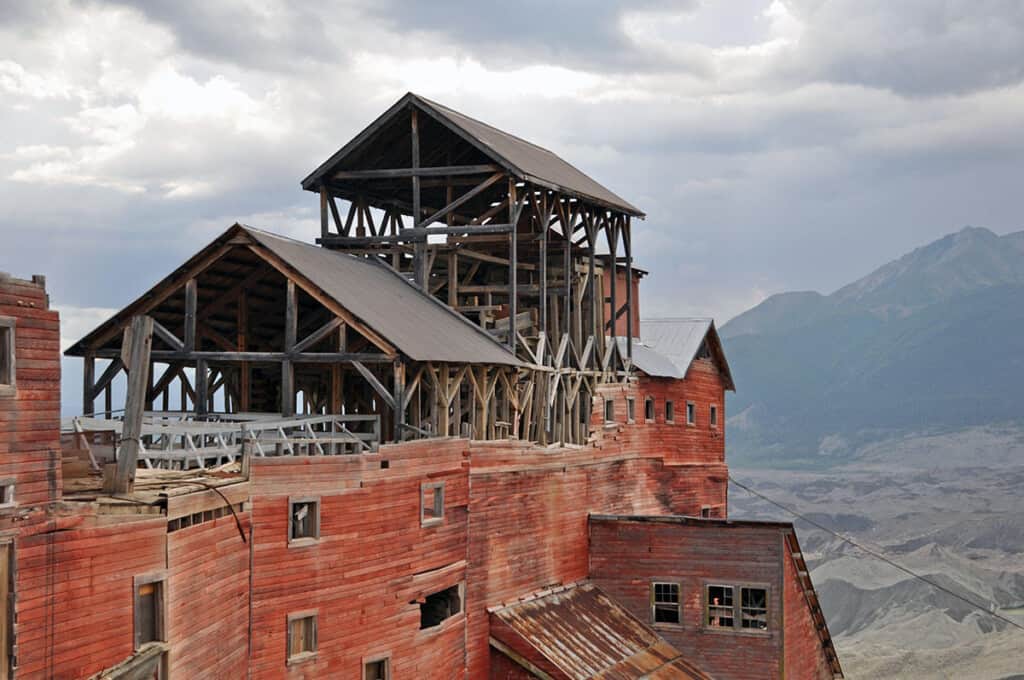 Explore some of the forbidden places in the us, tall wooden structure made up of several rooftops built on top of each other looking out across a vast valley with mountains in the distance