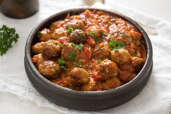 Discover the popular Spanish foods, Albondigas dish on table covered in white tablecloth
