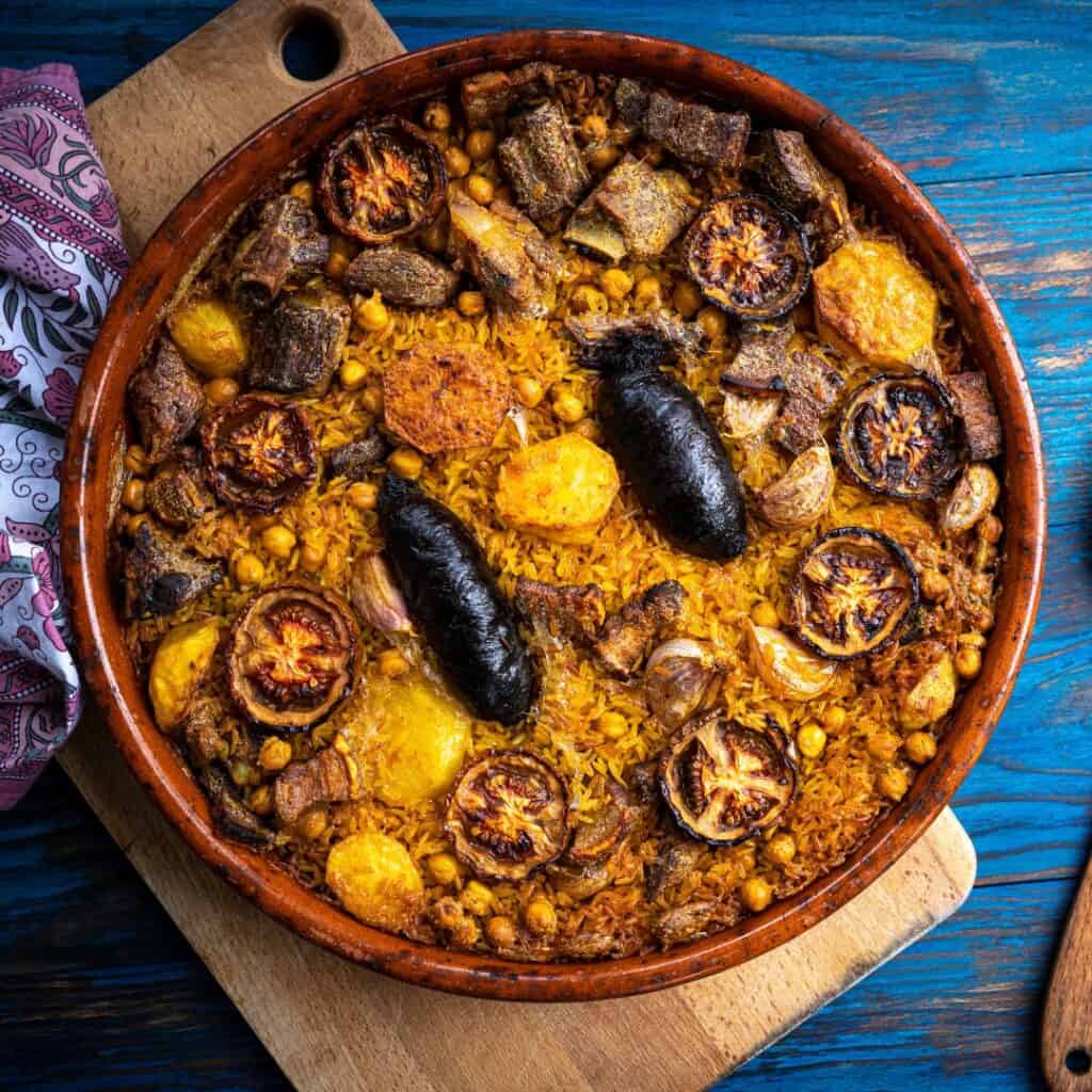 Spanish paella with sausages and mushrooms on a clay pot on a wooden table