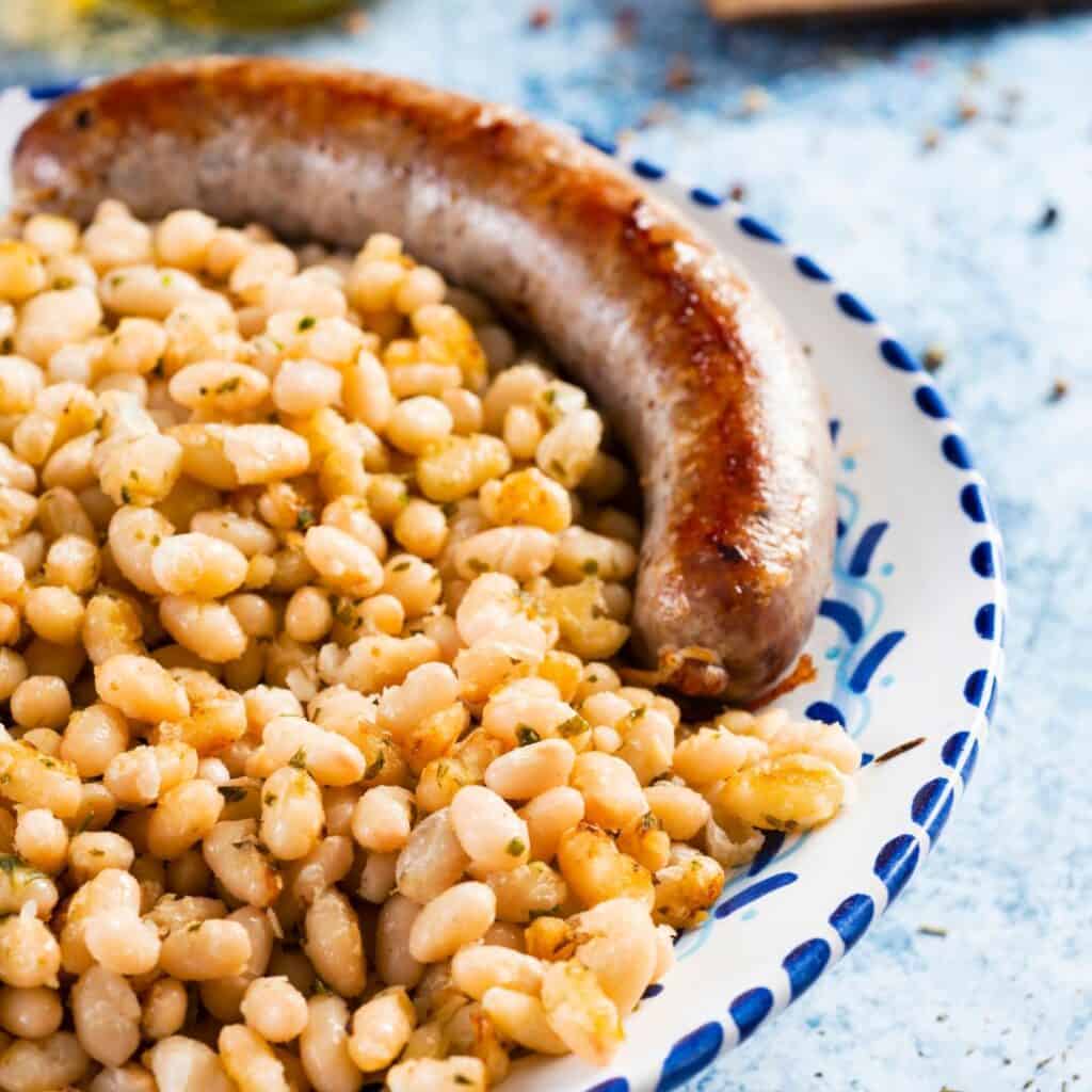 a plate with beans and a sausage on it