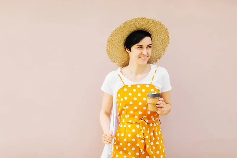 Young woman in straw hat with a mash bag of fruit and reusable coffee mug. Sustainable lifestyle. Plastic free concept.