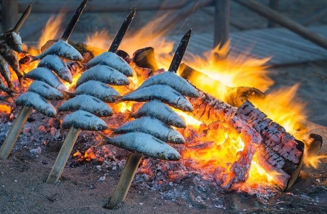 Espetos - Sardine skewers dish neing cooked by the sand on the beach