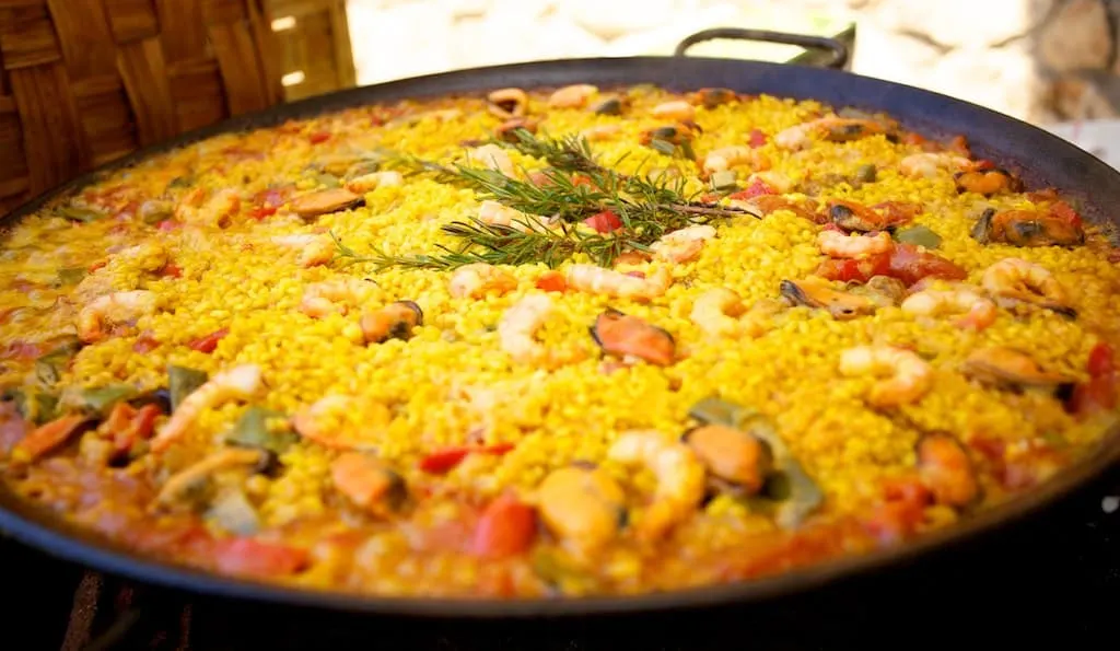 Paella dish from Valencia in large pan with seafood toppings and garnishes