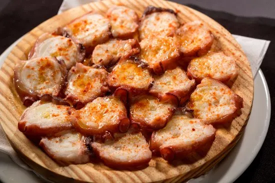 Pulpo a la Gallega dish sitting on a wooden plate