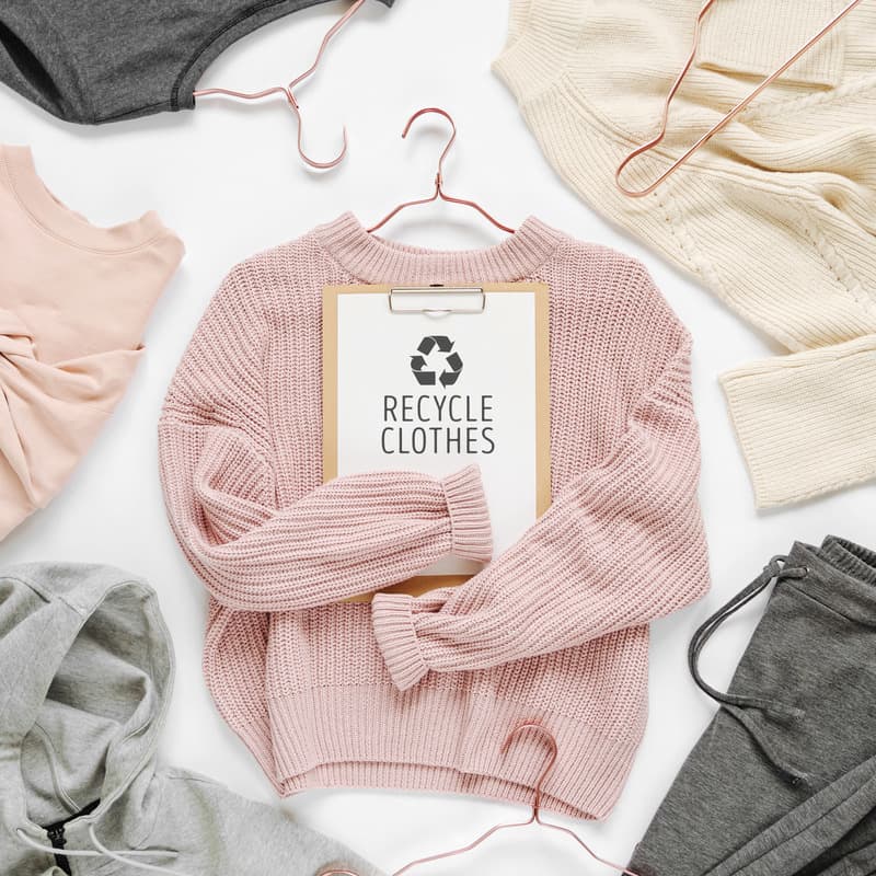 Concept de recyclage des vêtements. Pull en tricot rose pâle avec presse-papiers sur fond blanc. vêtements écologiques abordables