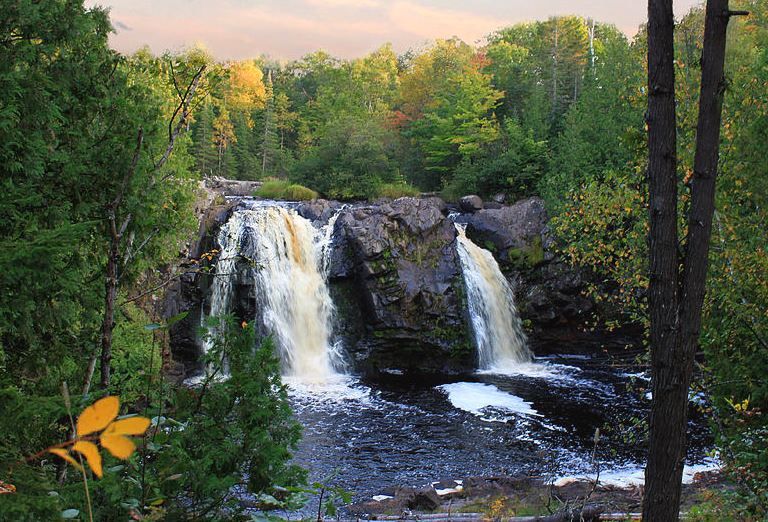 two pair of waterfalls in Little Manitou Falls, Pattison State Park with trees near autumn season