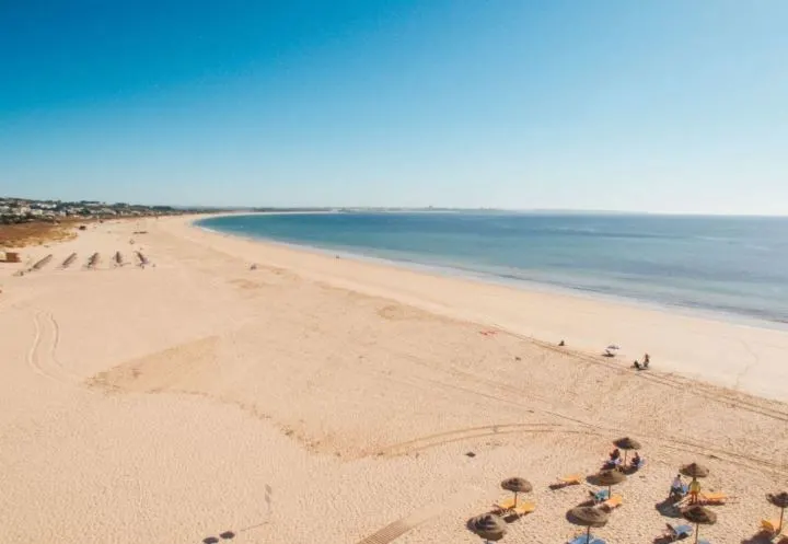 Best Beaches in Lagos Algarve, mostly empty sandy beach with some thatched umbrellas and beach chairs