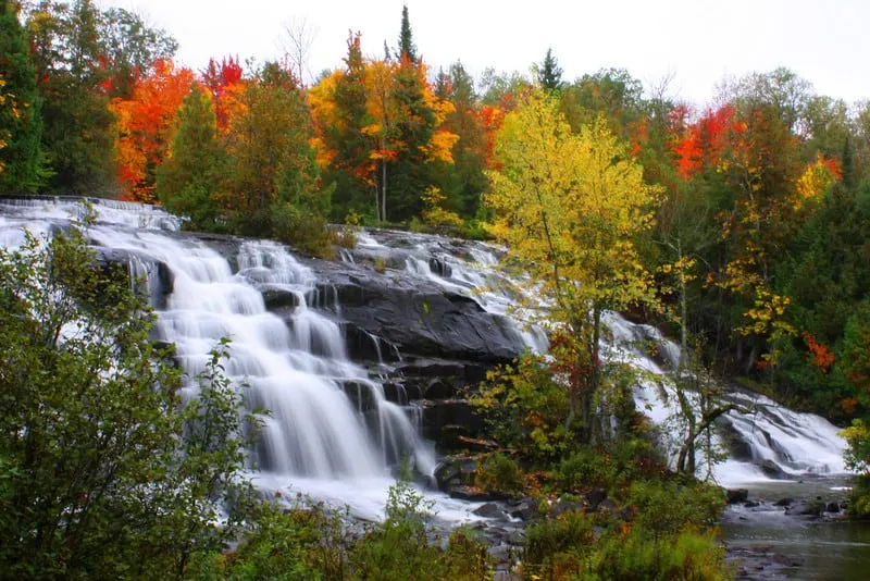 Try out some of these Wisconsin getaways for couples, Waterfalls of the Upper Peninsula of Michigan surrounded by trees in vibrant fall colors of green, yellow, orange and red