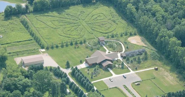 Cool places in appleton, WI, aerial view of Butterfly Gardens of Wisconsin with central building surrounded by green fields and trees with a large butterfly design carved into the top field