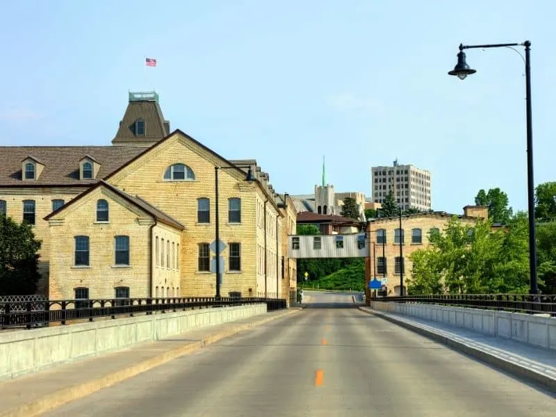 Try out these things to do in appleton, wi for adults, view of highway leading into Downtown Appleton with residential buildings to one side and taller buildings of the skyline visible in the distance all under a bright misty sky