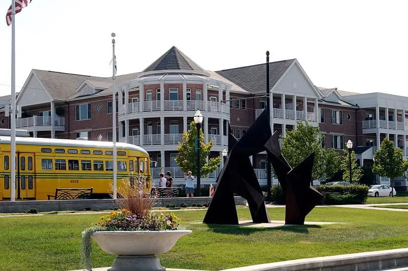 a sculpture in HarborPark with a bus and a large building at the back