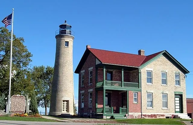 Southport Light Station Museum next to a light house and a flagpole with american flag in kenosha