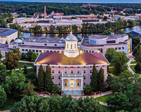 See all the appleton attractions, aerial view of Lawrence University campus with large central building with domed mini tower and more modern buildings behind interspersed with green trees and neat grass lawns with paved pathways