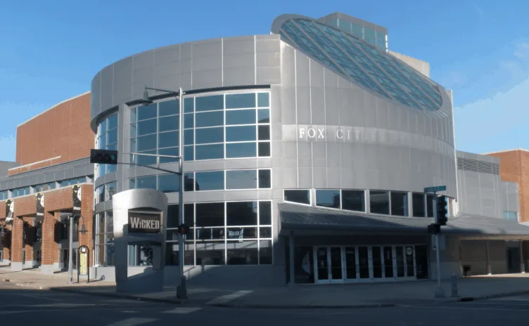 Fun things to do in Appleton, view of The Fox Cities Performing Arts Center (PAC) with large silver metallic curved walls and slanted glass ceiling area situated on a street corner in downtown Appleton, Wisconsin 