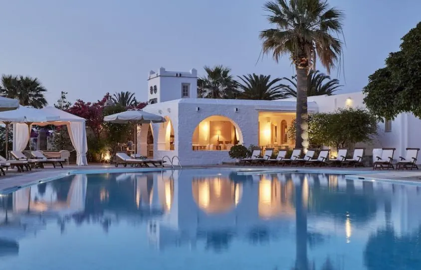 a view of the pool with a canopt and beach chairs and a bar with a light and trees