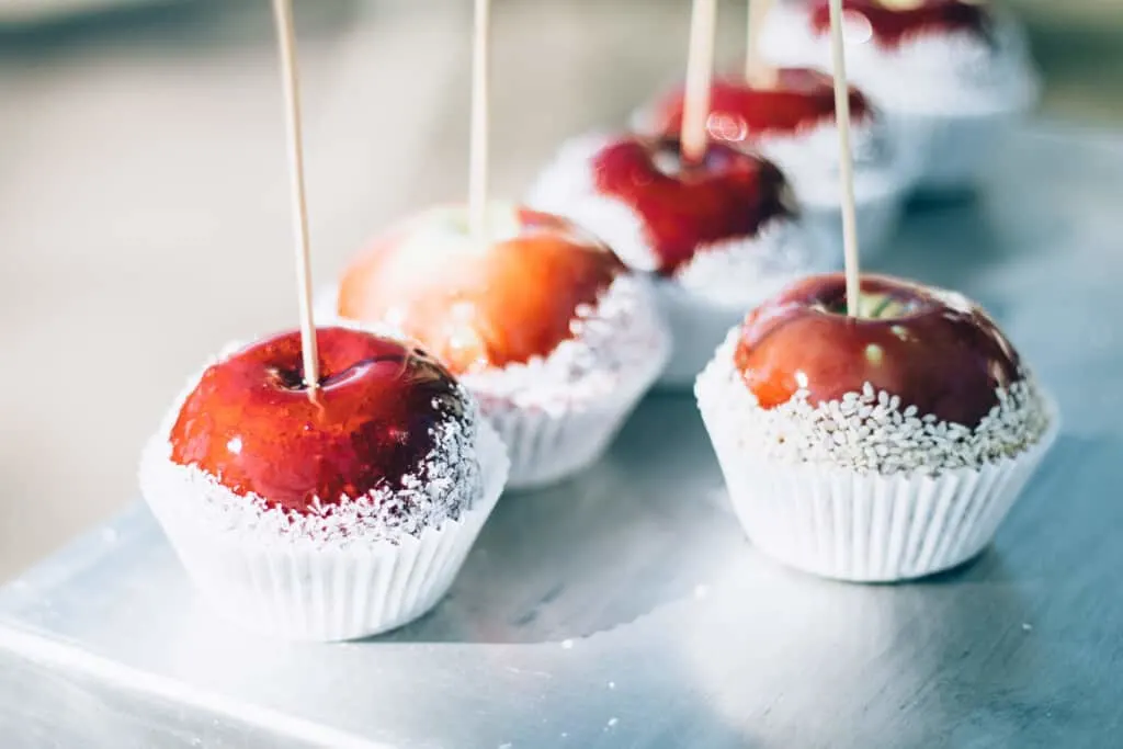 Head to the best festivals in milwaukee this October, close up shot of candied apples wrapped in white cupcake wrappers sitting on a metal tray