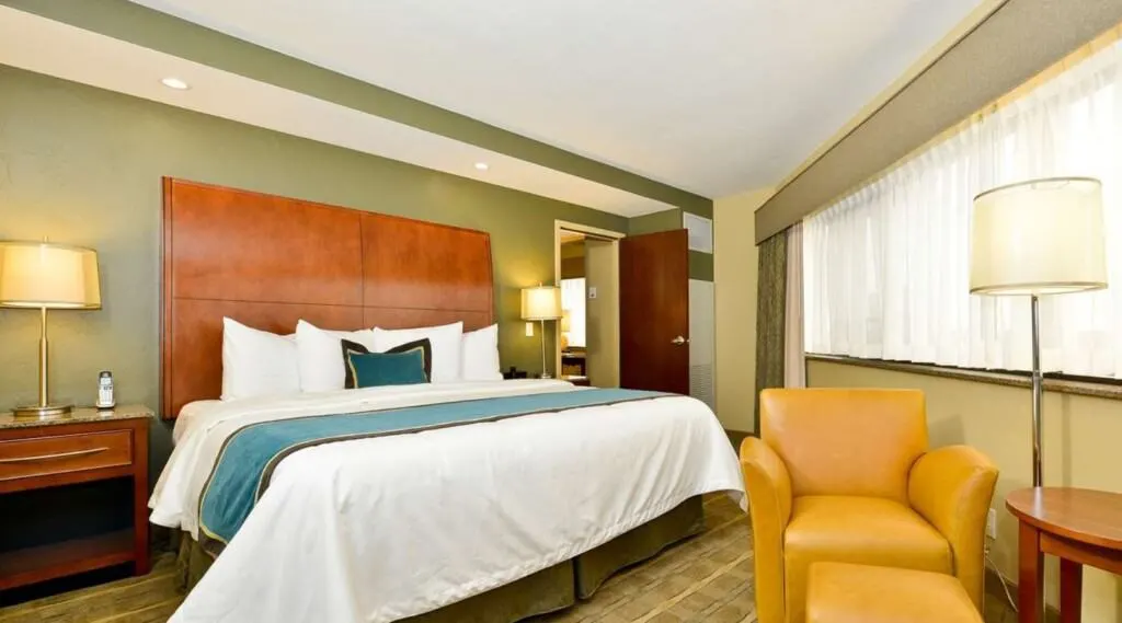 best wisconsin resorts with lake view, king bed and lounge chair inside of room at best western oshkosh wisconsin resort