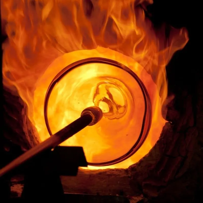 a view of a glass being burned or blowed in a big orange flame