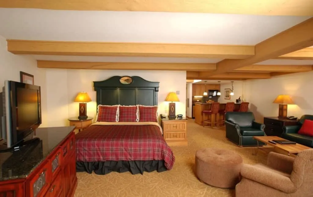 luxury lake resorts in wisconsin, room at lake lawn resort with bed, tv, sofa, chairs and kitchen