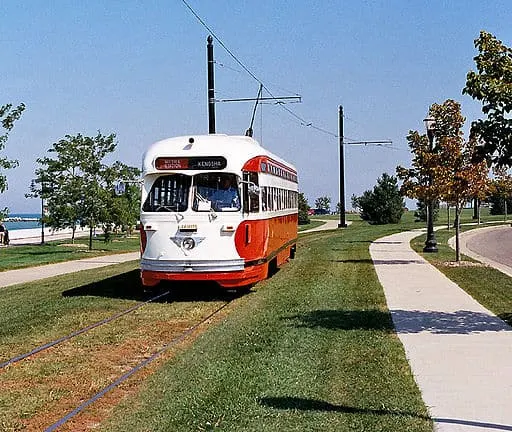 a red and white streetcard moving during a bright day