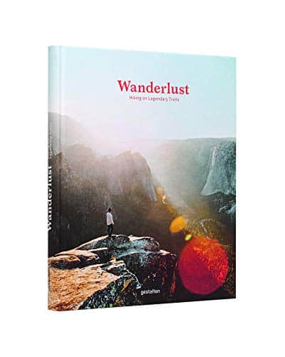 Yellowstone book, book cover showing person standing on large outcrop of rock in front of breathtaking view of mountain range with sunlight beaming down from the ridge creating an artistic lens flare