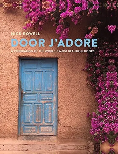 Decorative travel books, book cover showing blue painted wooden door set in clay coloured wall with vibrant purple flowers running up the wall beside it