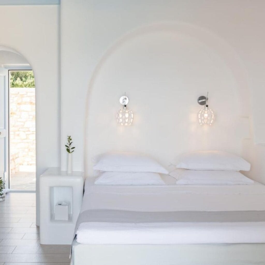 a white bedroom with white walls and a white queen bed with a door at Calme Boutique Hotel