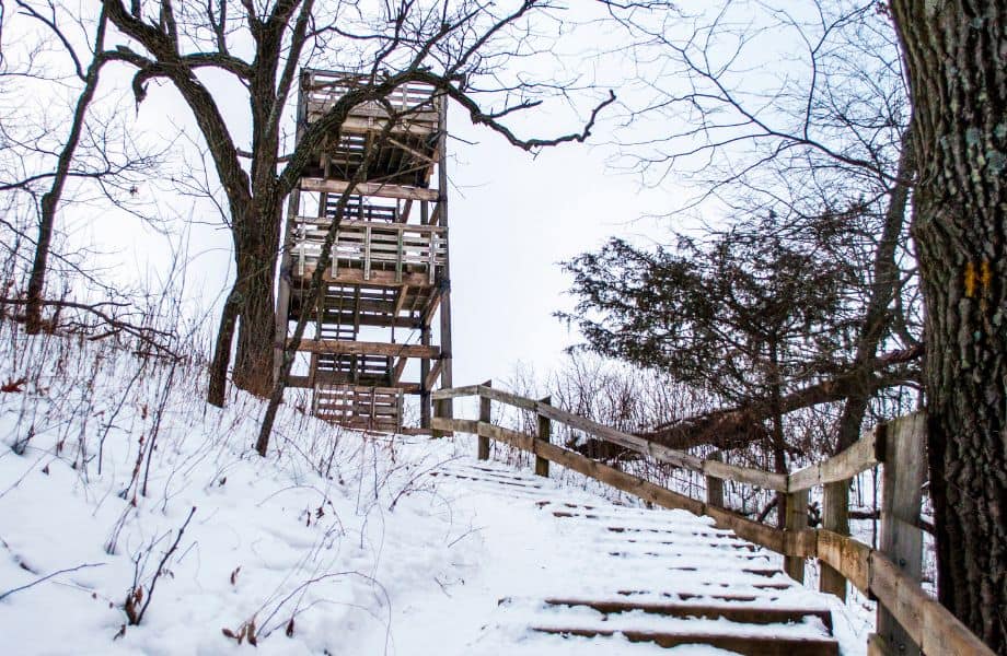 Head out on some wisconsin weekend getaways in the fall, wooden tower structure at top of wooden stairs on side of hill all covered in snow